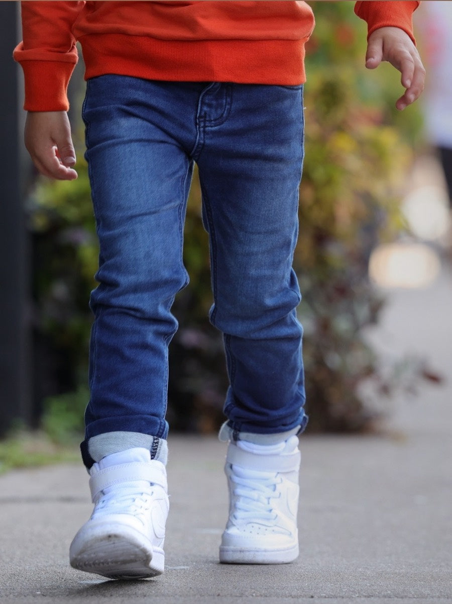 Child walking down a sidewalk in GILi Guise denim jeans and white sneakers